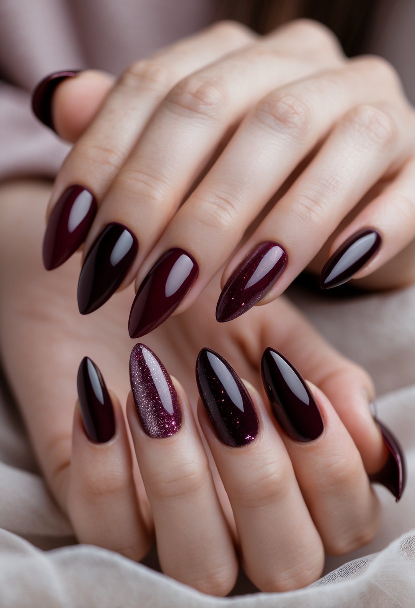 Close-up of hands with almond-shaped nails painted in five different deep wine red and burgundy designs.