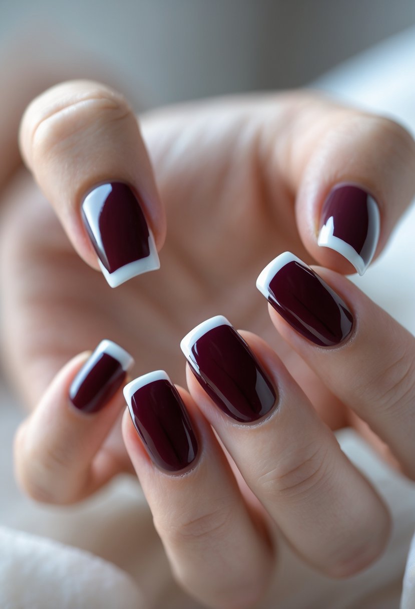 Close-up of a hand showing five square burgundy nails with white French tips.