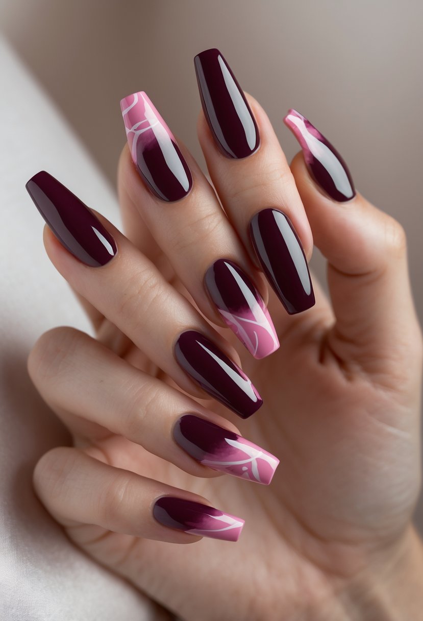 Close-up of a hand with six coffin-shaped nails painted deep burgundy with abstract pink designs.